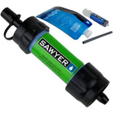 Sawyer Mini water filter in green and black, angled view, with blue squeeze pouch, cleaning syringe and drinking straw.
